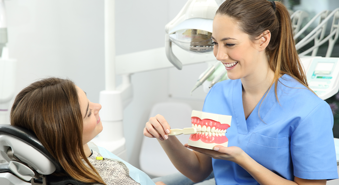 Tandplejer der viser en patient hvordan man børster tænder korrekt