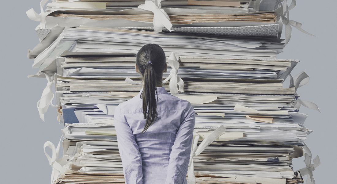 Pige foran en stor stak dokumenter